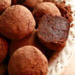 Close up view of a small white plate piled with homemade dark chocolate truffles.