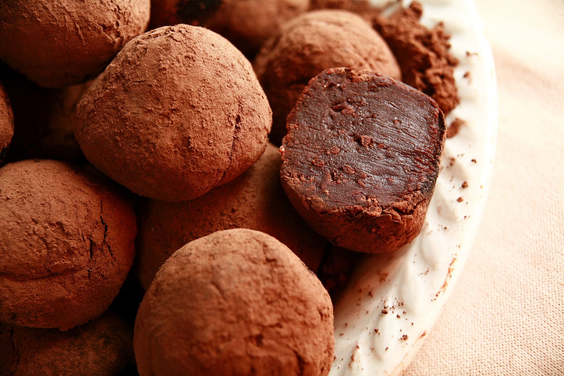 Close up view of a small white plate piled with homemade dark chocolate truffles.