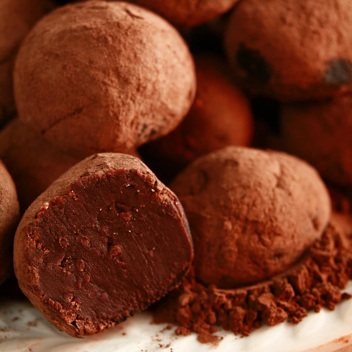 Close up view of a small white plate piled with homemade dark chocolate truffles.