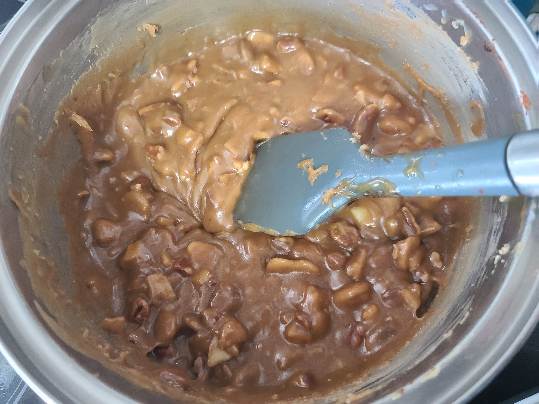 A silicone spatula being used to stir the praline mixture.