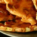 Chunks of pistachio brittle on a green plate.