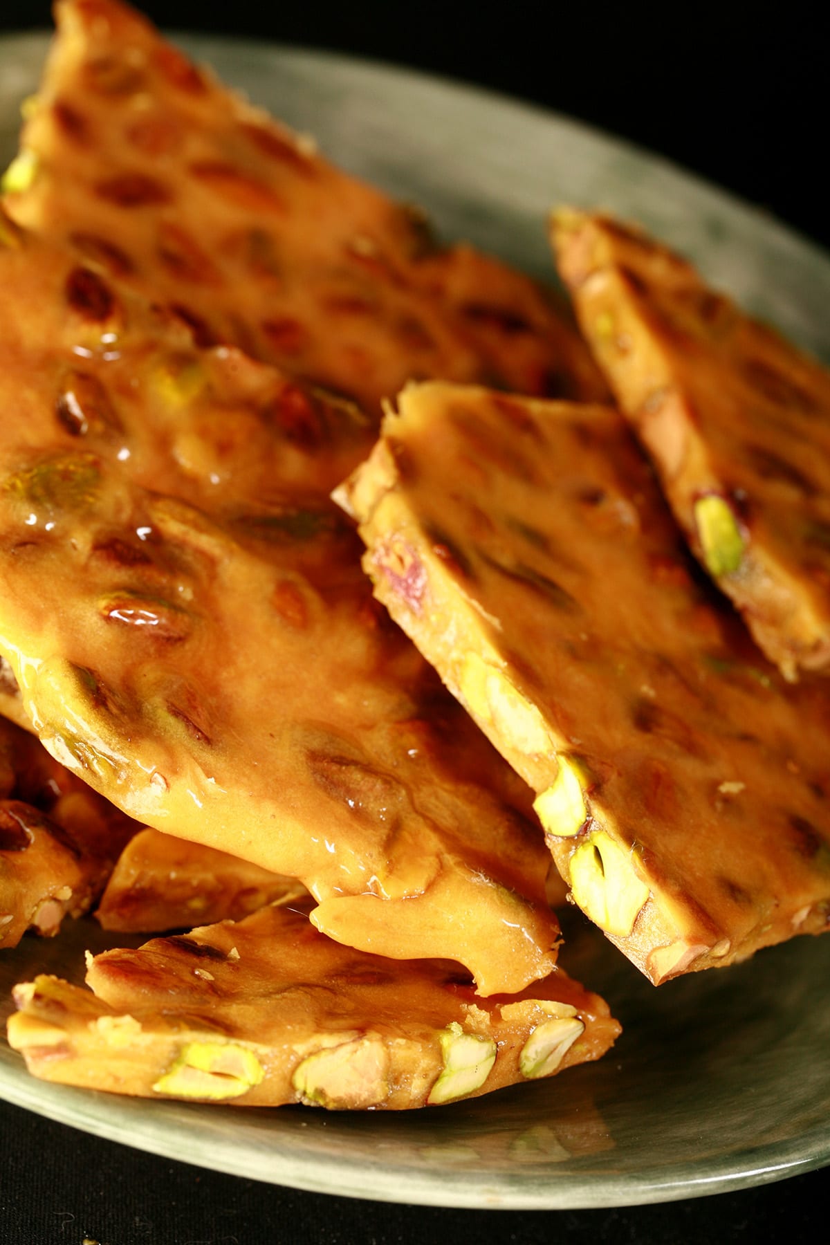 Chunks of pistachio brittle on a green plate.