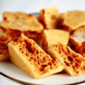 Close up view of a plate of golden honeycomb toffee chunks.