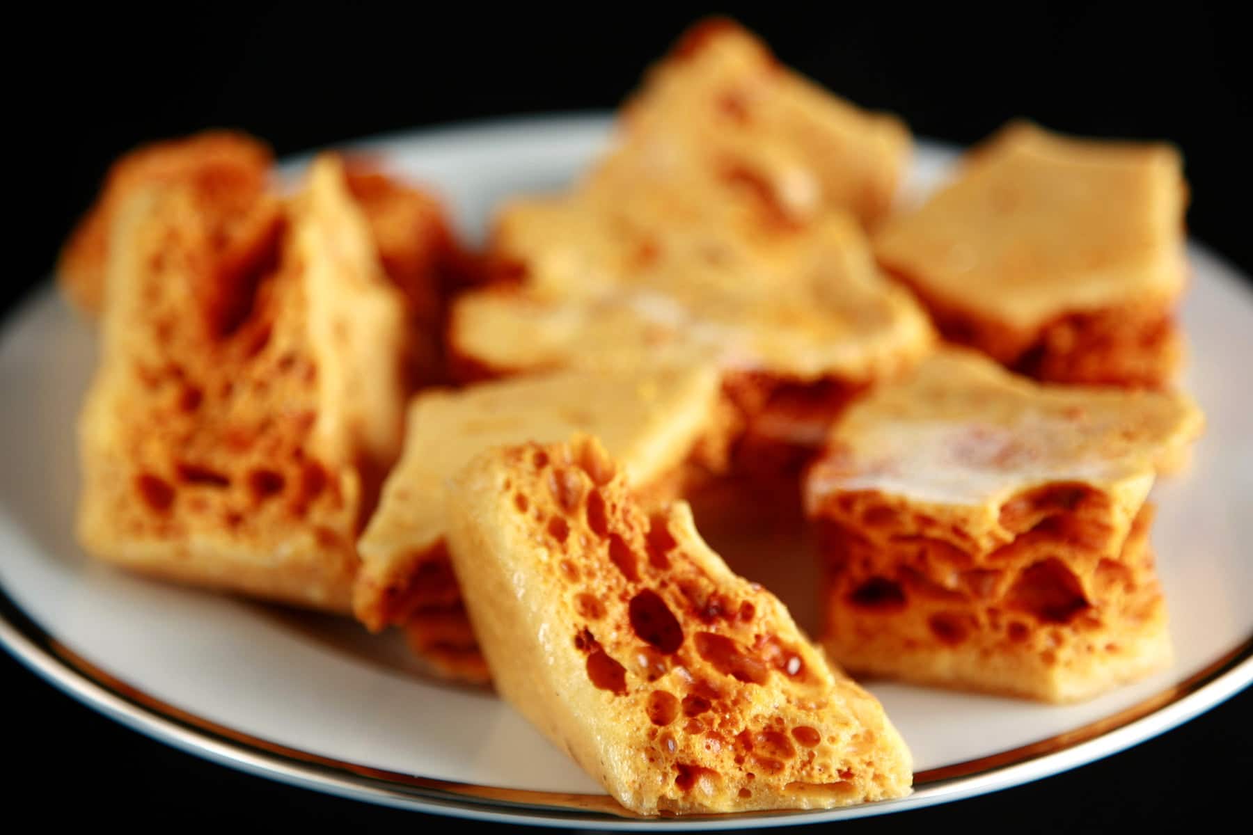 Close up view of a plate of golden honeycomb candy chunks.