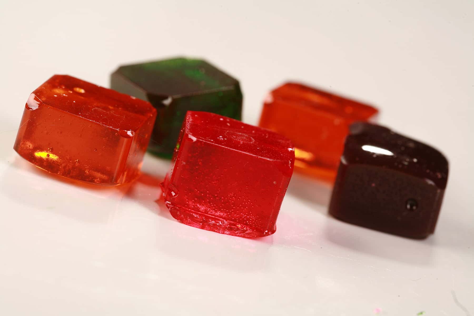 5 squares of colourful hard candy are shown on a white background.