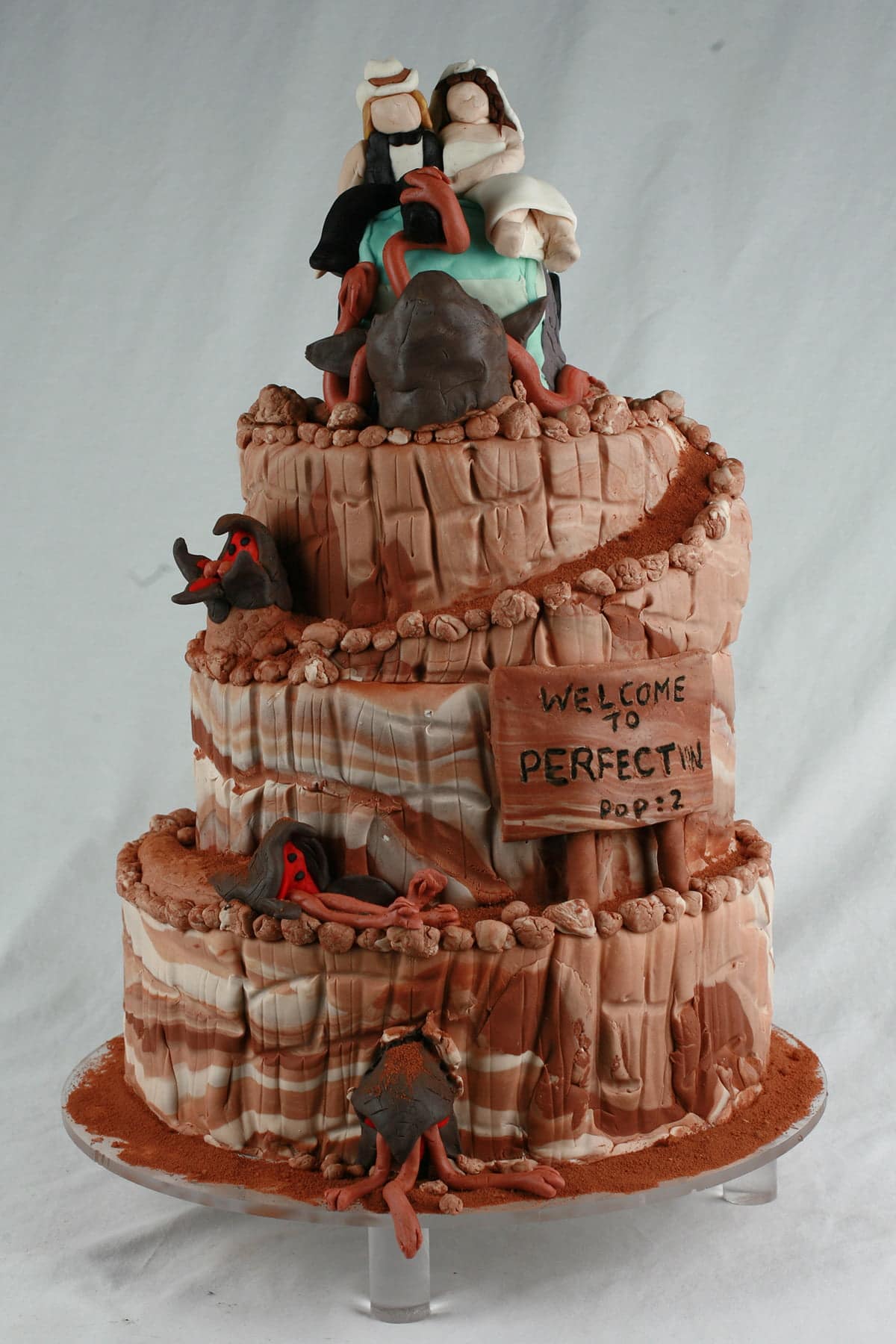 Detail photos of a "Tremors" themed wedding cake, almost entirely decorated in various shades of chocolate fondant.