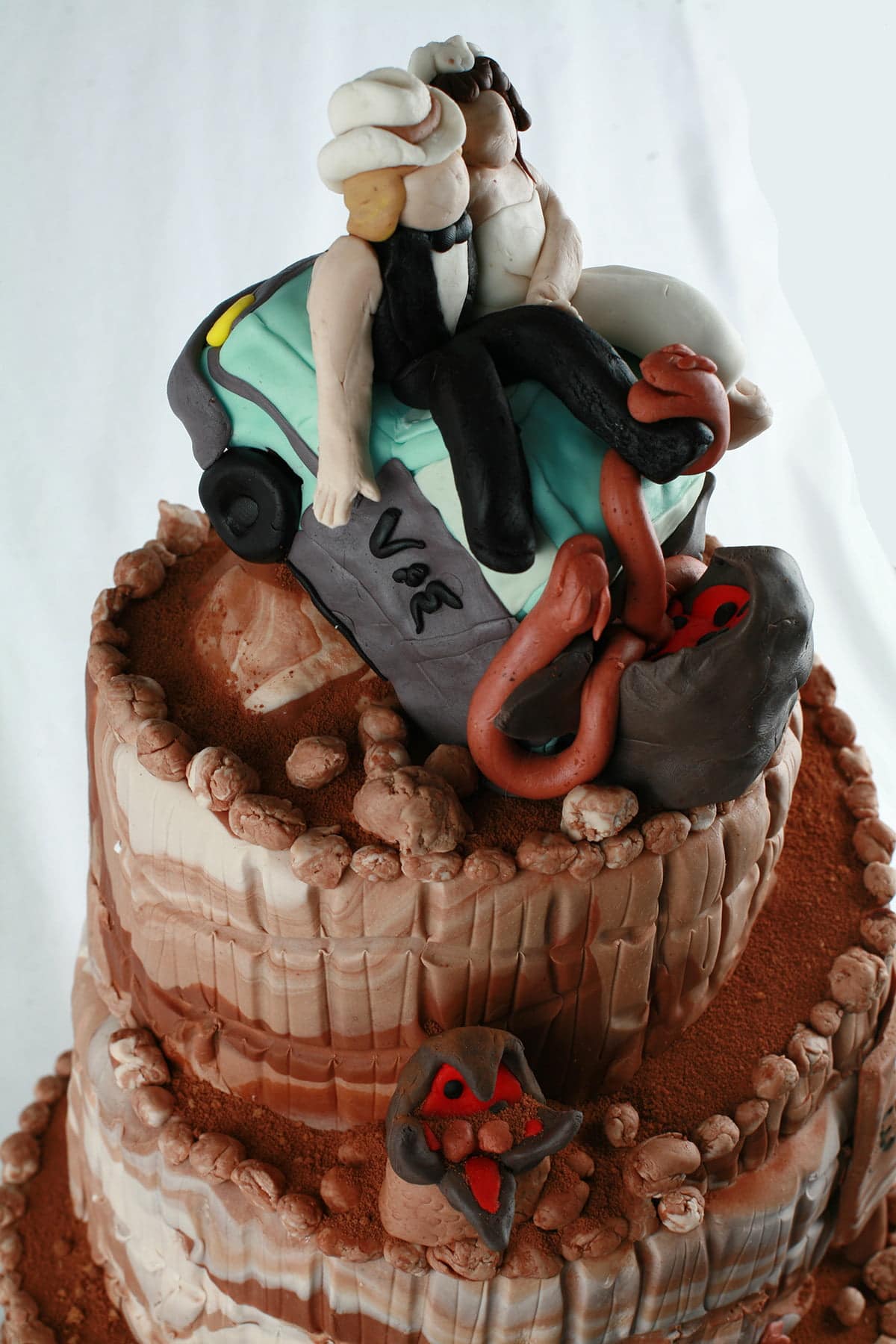 Detail photos of a "Tremors" themed wedding cake, almost entirely decorated in various shades of chocolate fondant.