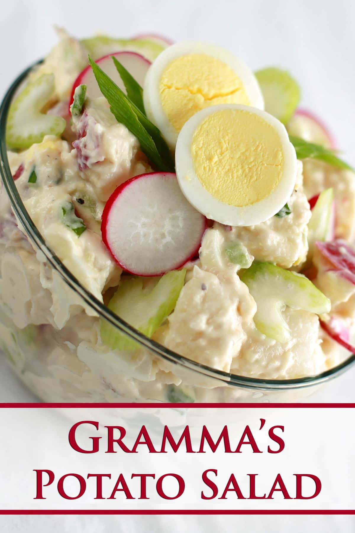 A bowl of Gramma's Potato Salad - a creamy potato salad with slices of celery, radish, green onion, and hardboiled egg visible.