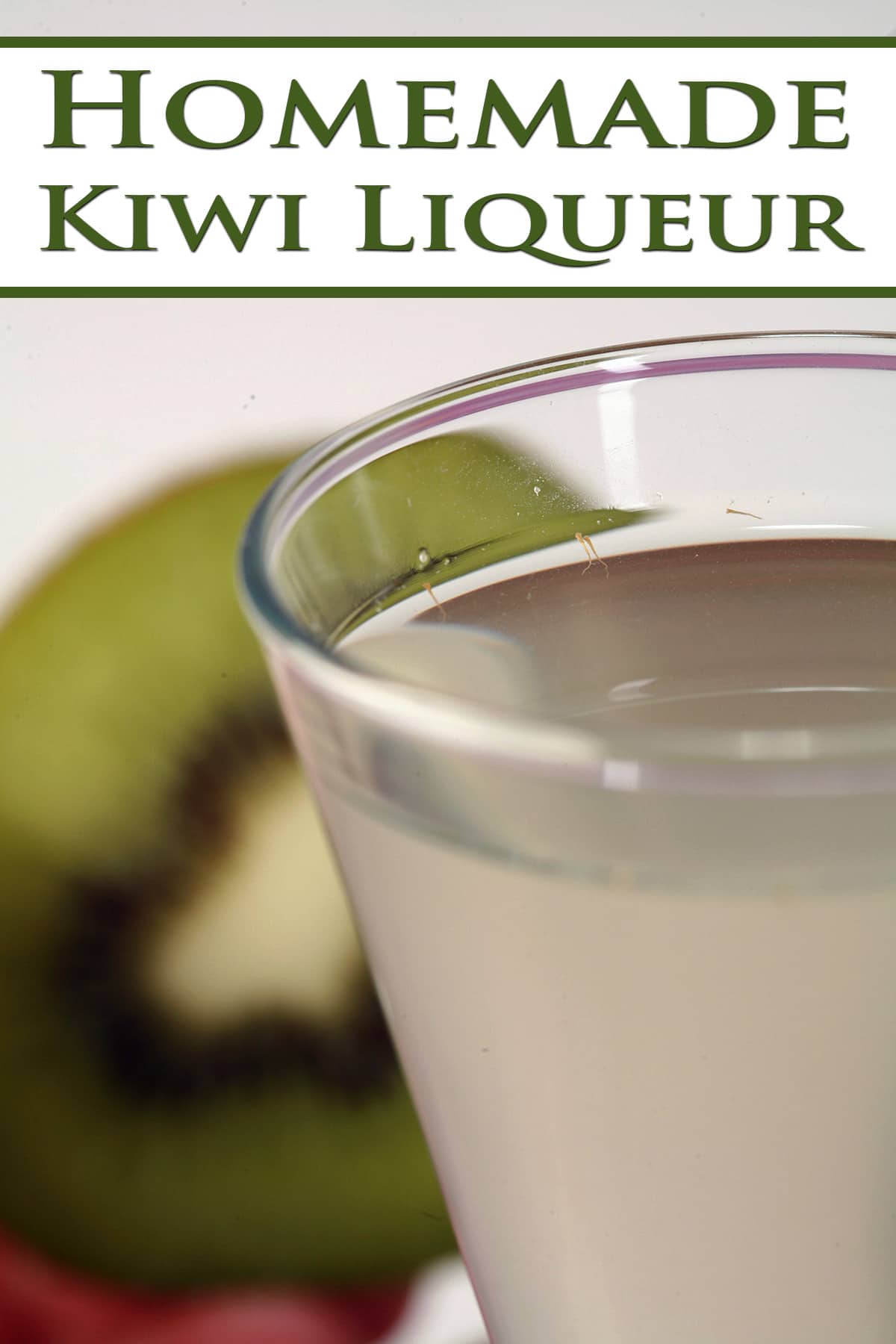 A fancy shot glass of homemade kiwi liquer.  There is a sliced open kiwi behind it.