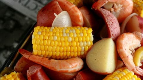 A close up view of a batch of frogmore stew: Red potatoes, corn on the cob, shrimp, and sausage.