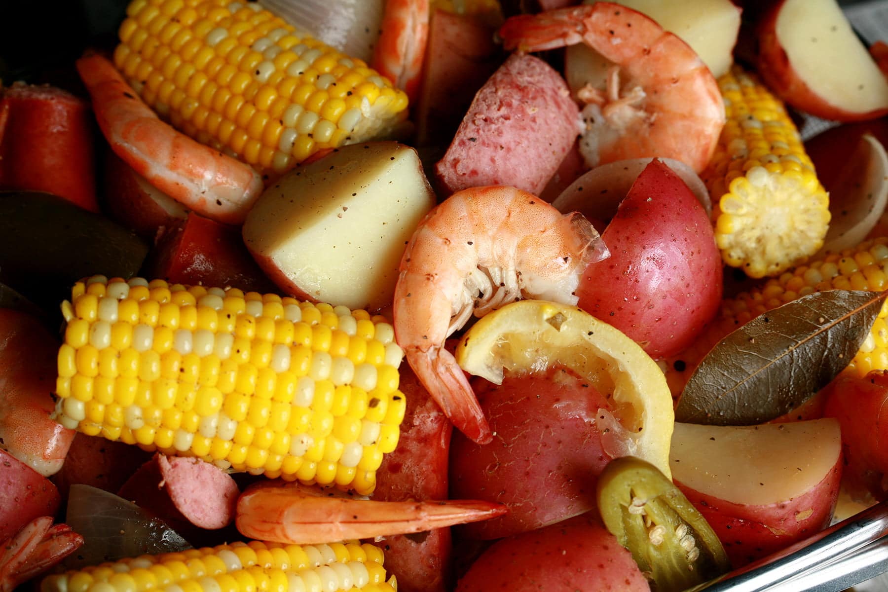 A close up view of a batch of frogmore stew: Red potatoes, corn on the cob, shrimp, and sausage.