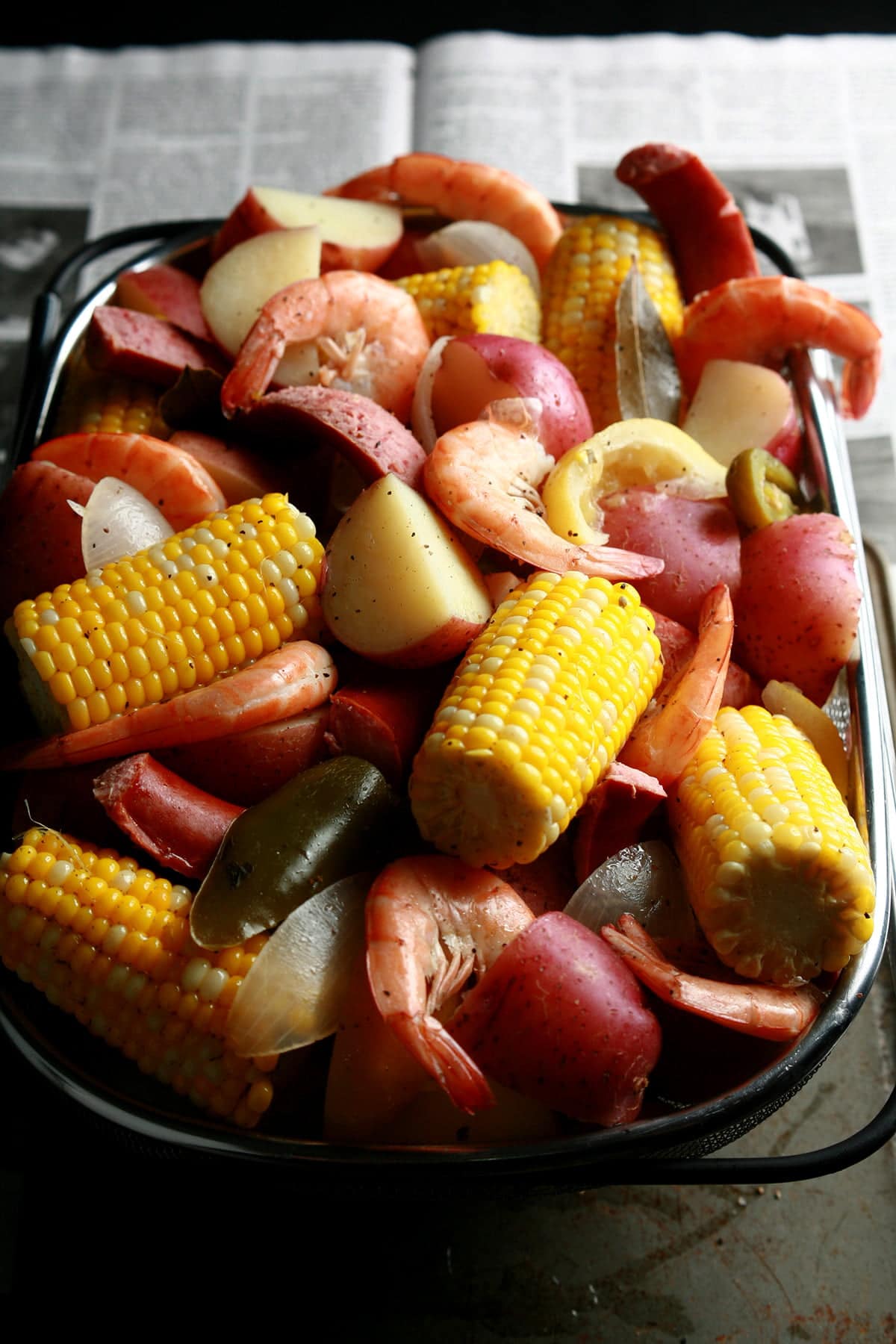 A close up view of a batch of low country boil: Red potatoes, corn on the cob, shrimp, and sausage.