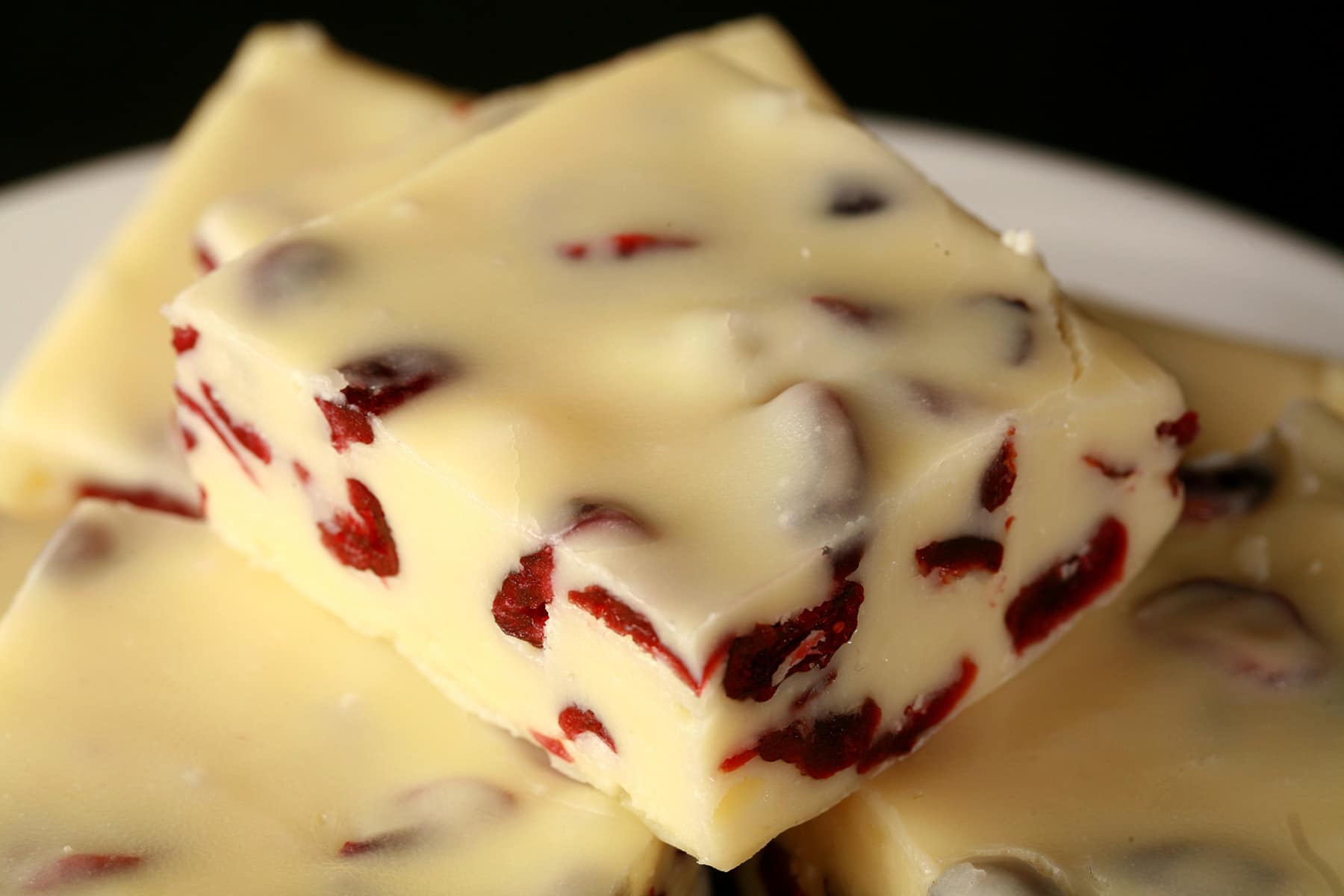 A plate with a pile of orange cranberry white chocolate fudge.