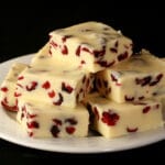 A plate with a pile of orange cranberry white chocolate fudge.