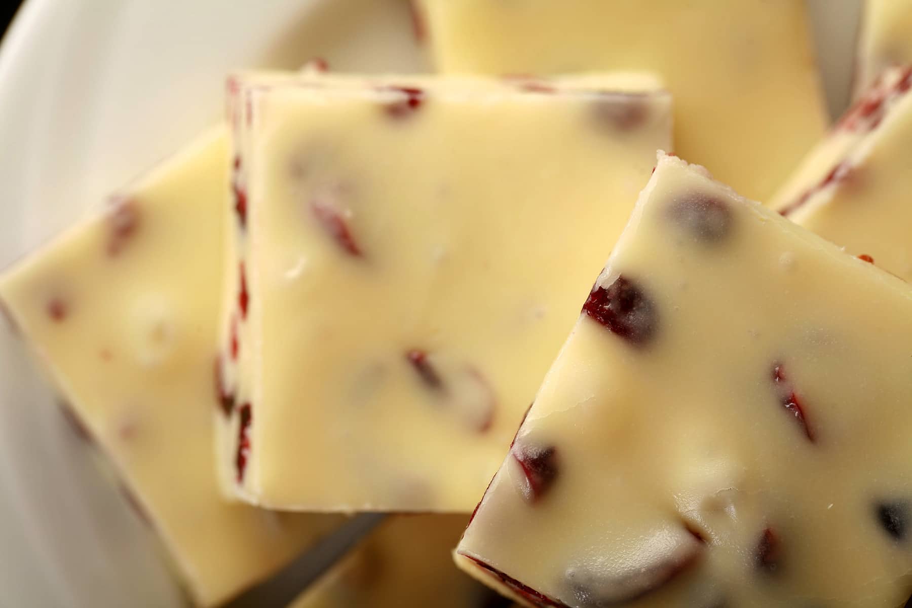 A plate with a pile of orange cranberry white chocolate easy fudge.