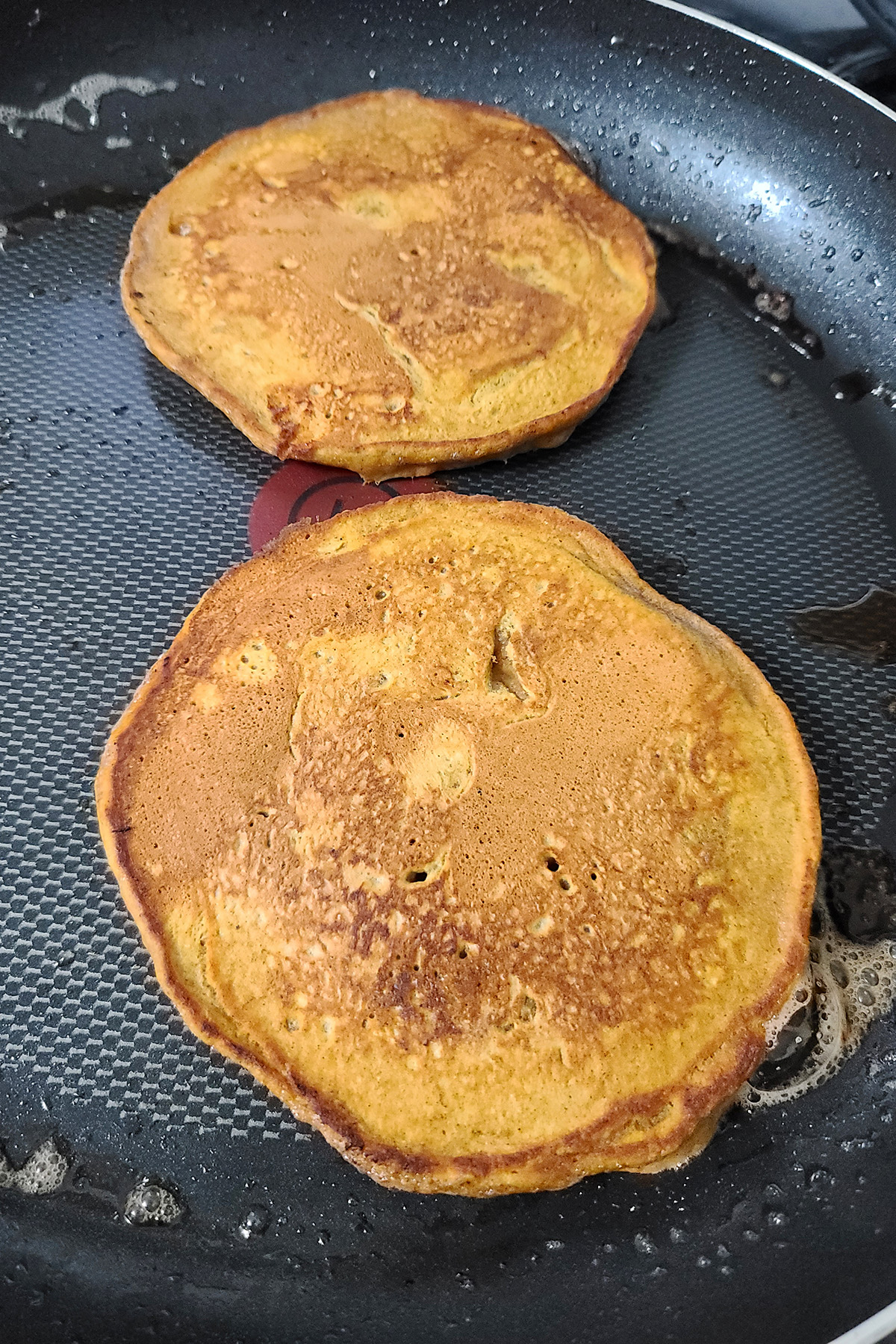 Pumpkin pancakes in a pan.