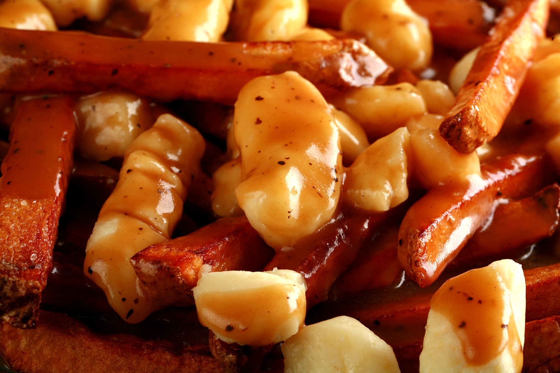 A close up view of poutine - fries, white cheese curds, and gravy.