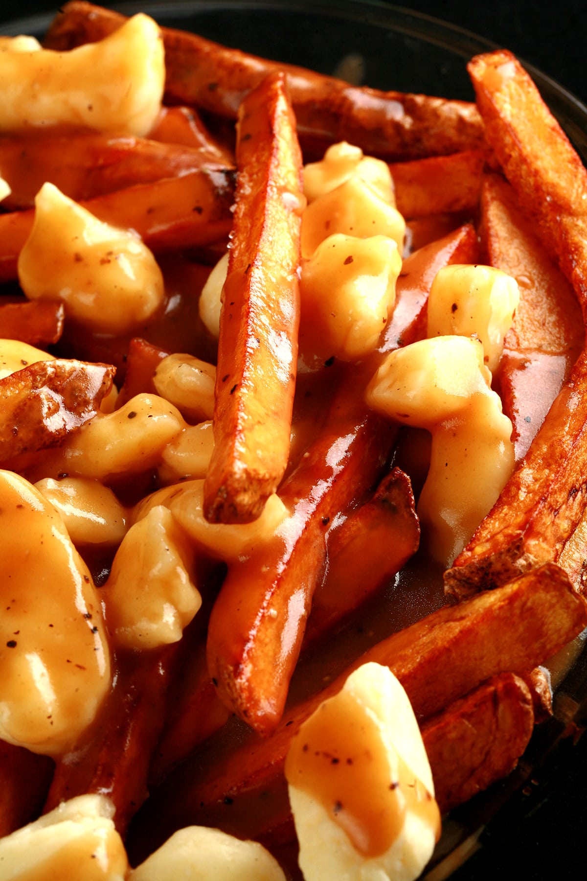 A close up view of poutine - fries, white cheese curds, and gravy.