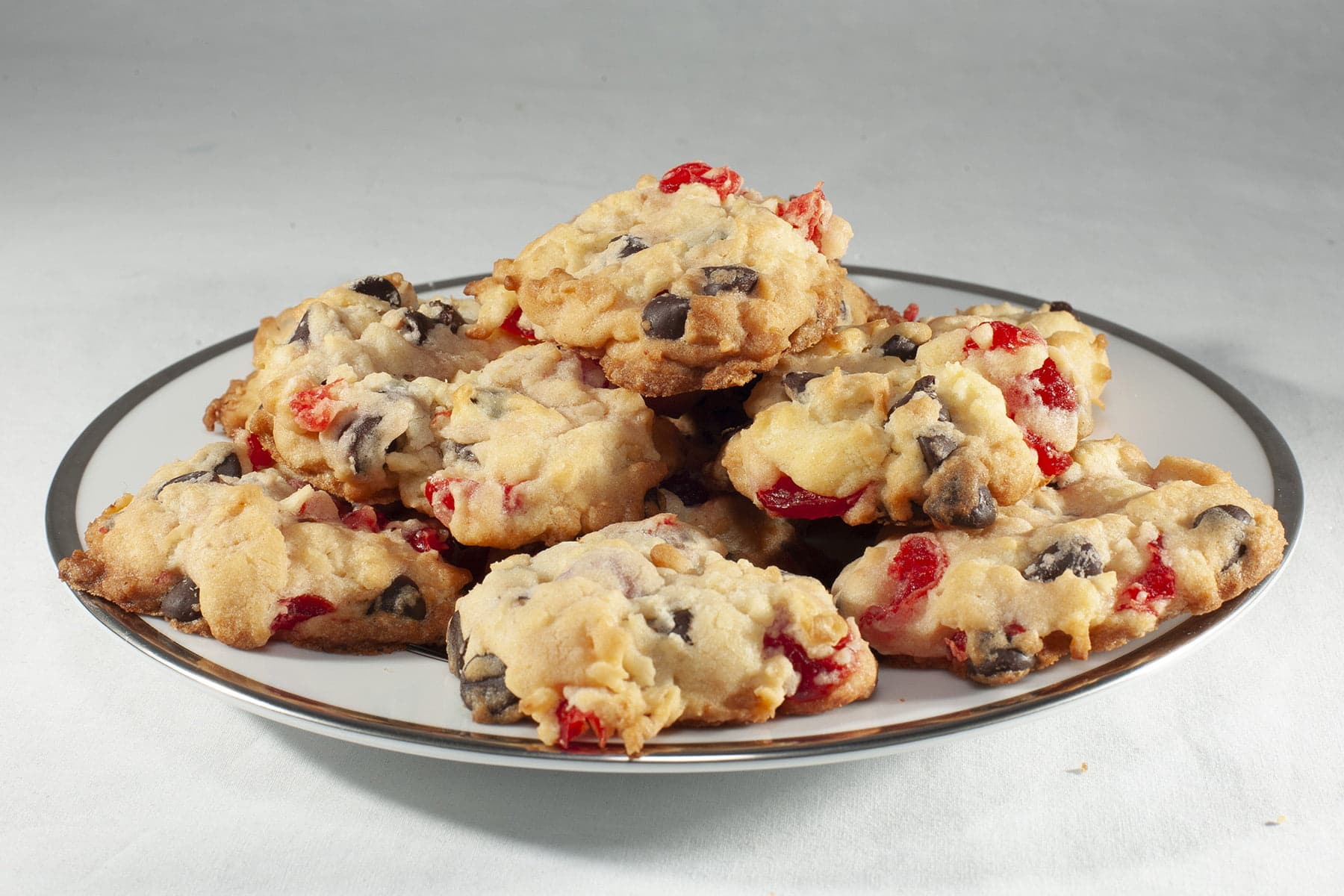 A plate of "Noelles" cookies - Lighty coloured drop cookies, with chocolate chips and pieces of maraschino cherries visible.