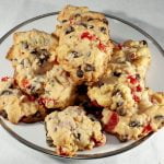 A plate of "Noelles" cookies - Lighty coloured drop cookies, with chocolate chips and pieces of maraschino cherries visible.