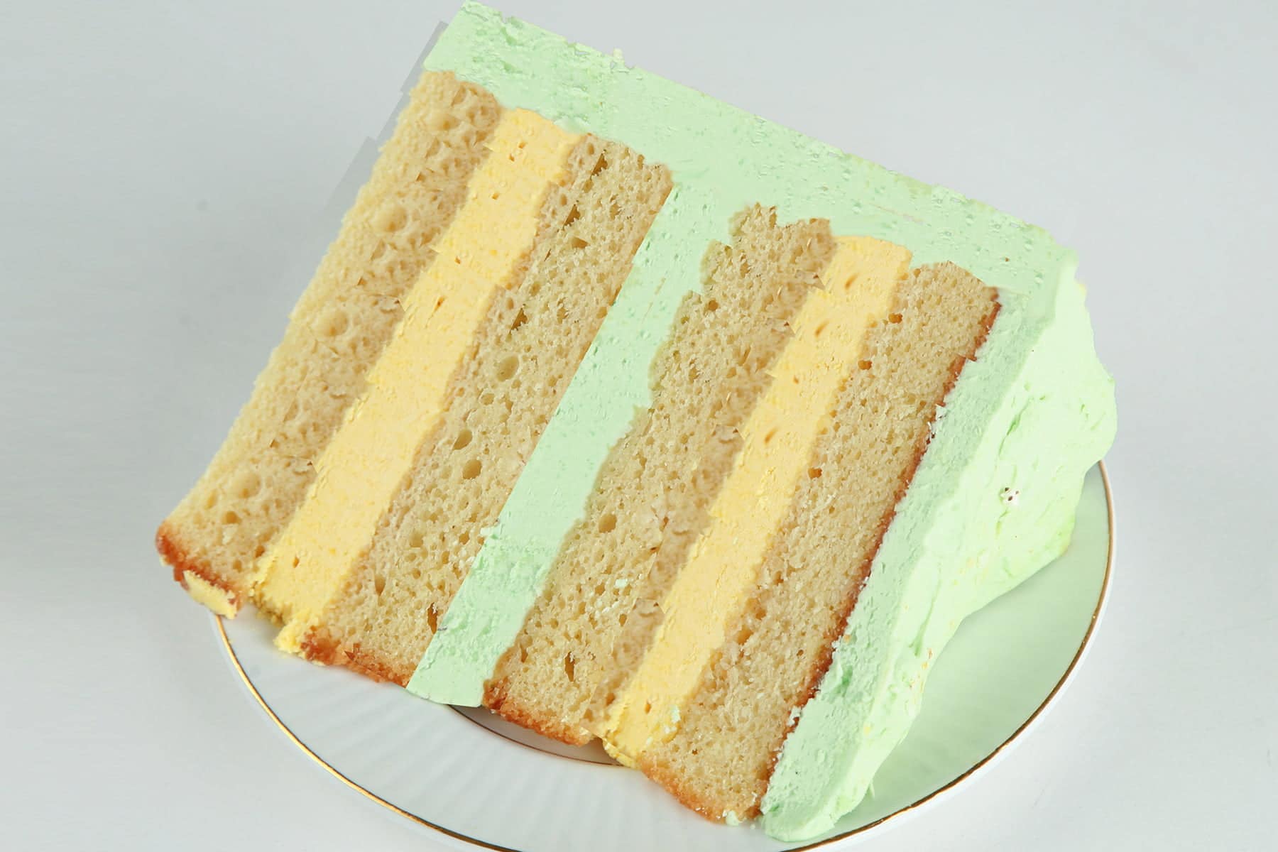 A slice of mango mojito torte. 4 layers of a mango rum cake, separated by layers of mango and mint buttercream.