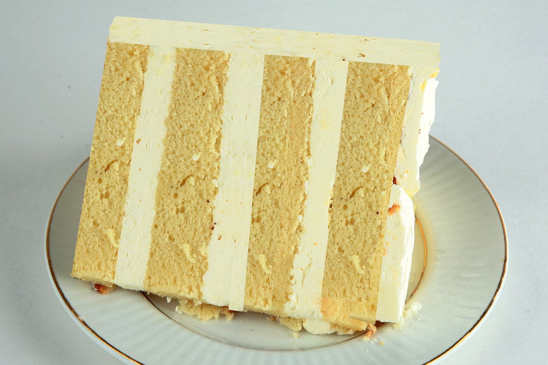 A slice of white chocolate amaretto cake.  4 layers of a yellowish cake, separated by layers of white chocolate buttercream.