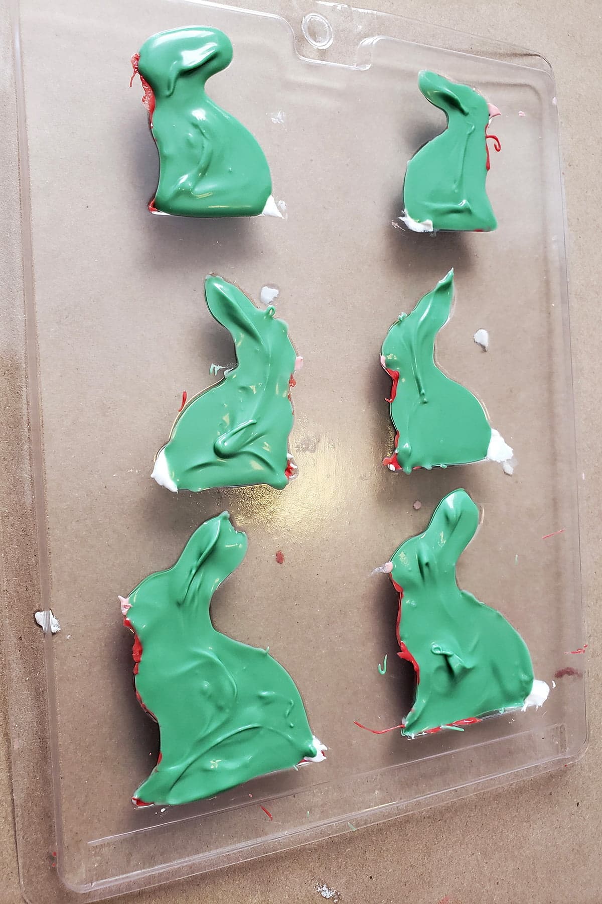 A plastic mold with 6 bunny shaped cavities is shown filled up with green melted candy.