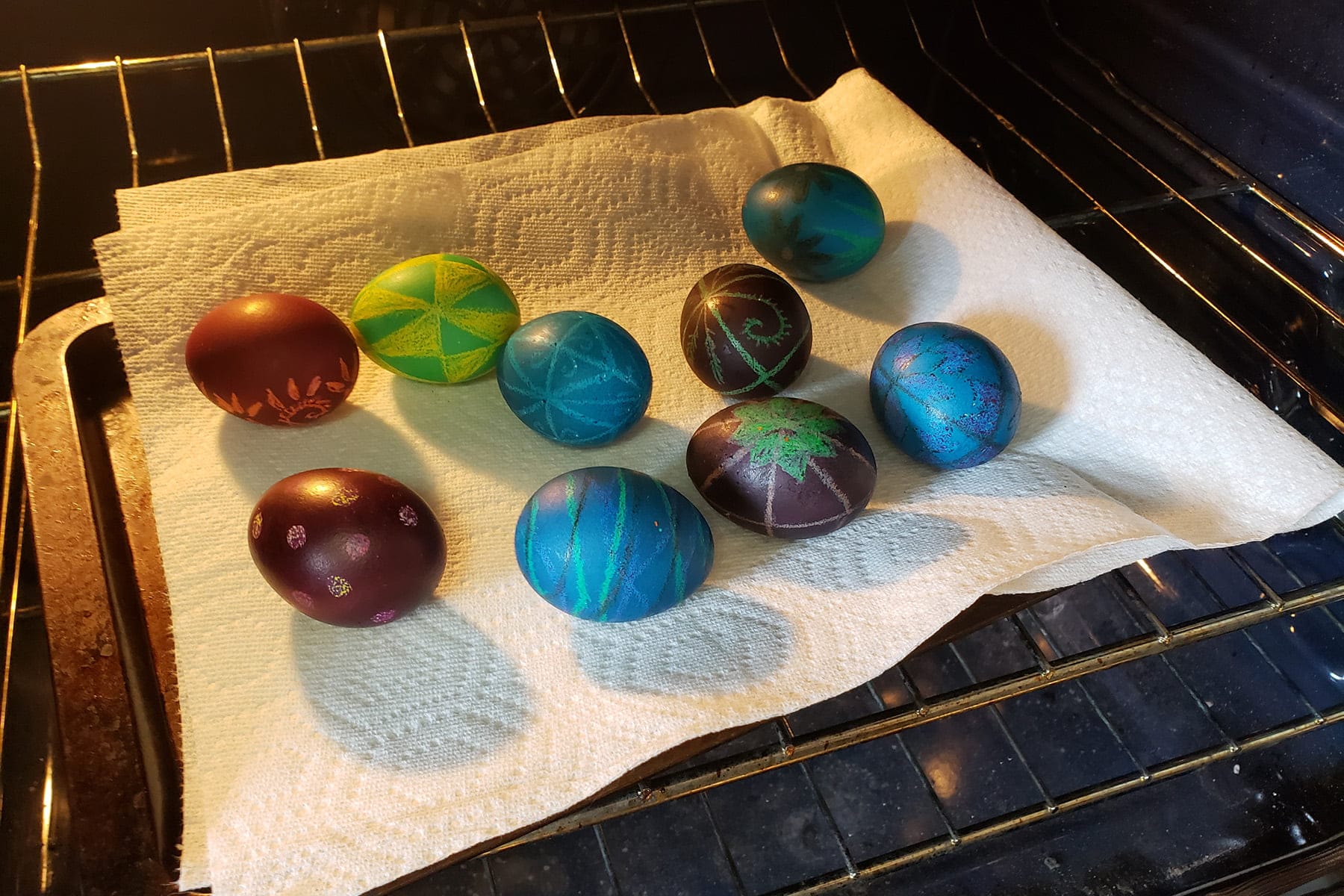 9 eggs are spaced out on a cookie sheet that's lined in paper towels. It is in the oven.