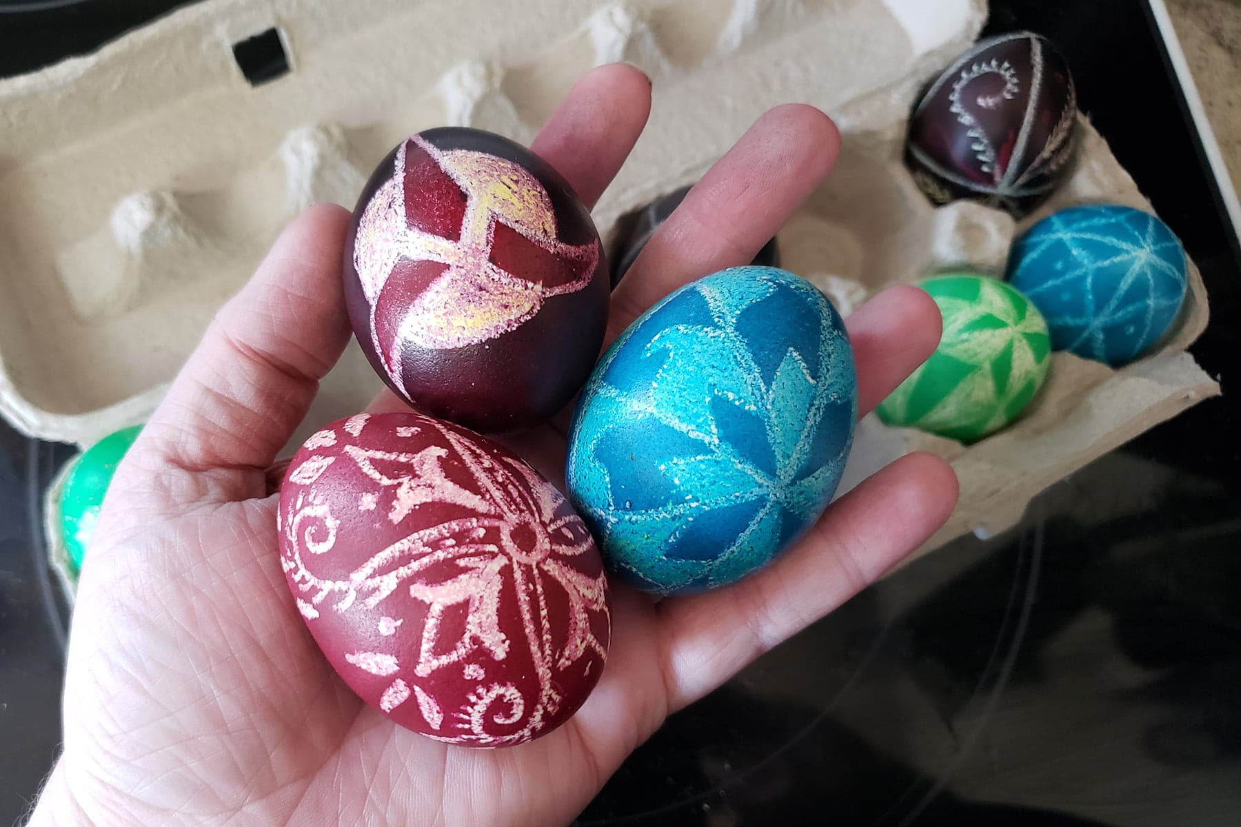 A hand holds 3 Ukrainian Easter eggs - one red, one blue, and one with a Klingon symbol on it.