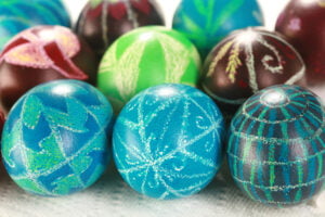 Several brightly coloured wax relief dyed pysanky easter eggs, on a white background.