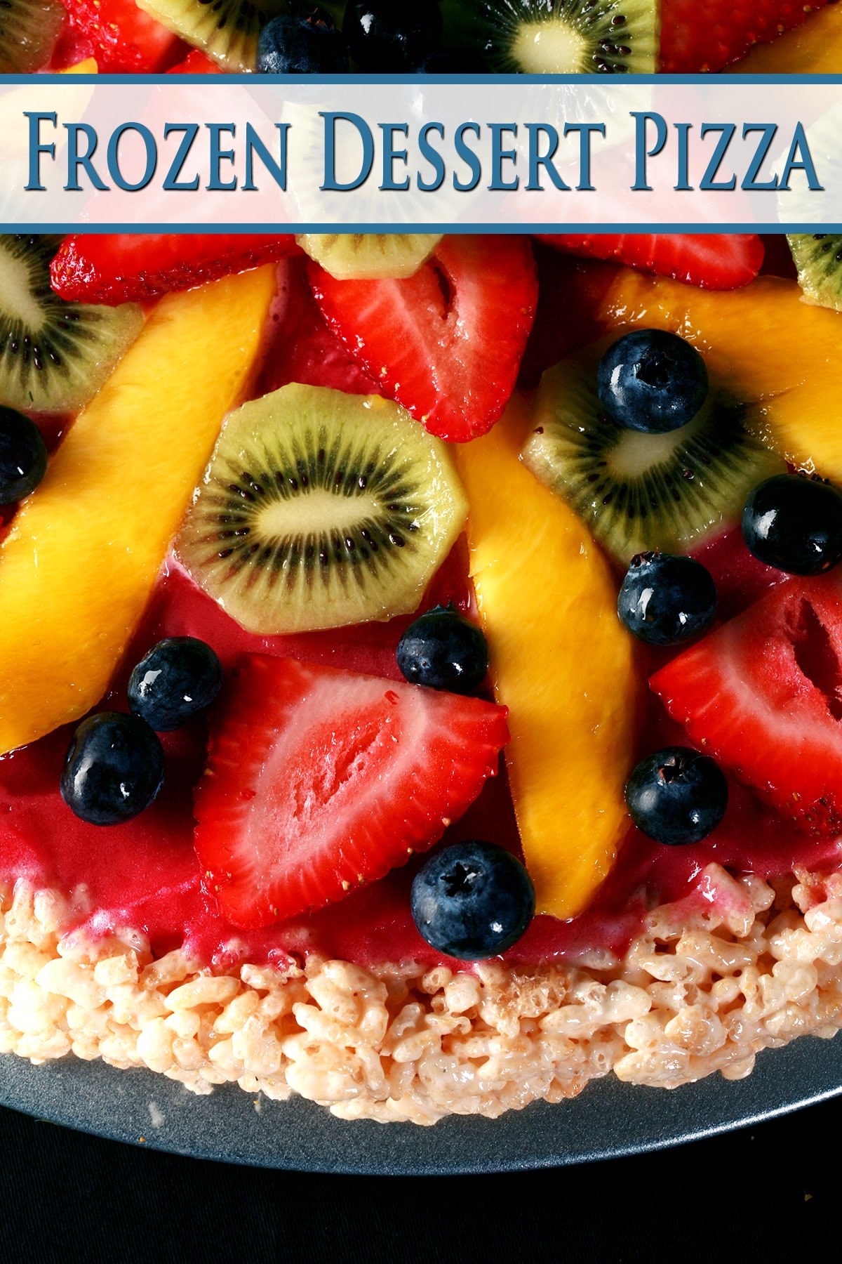A close up view of a frozen dessert pizza: Rice Crispy Treat crust, dark pink sorbet, and brightly coloured fruit in concentric circles. Kiwi slices, blueberries, strawberry slices, and long slices of mango are all featured.