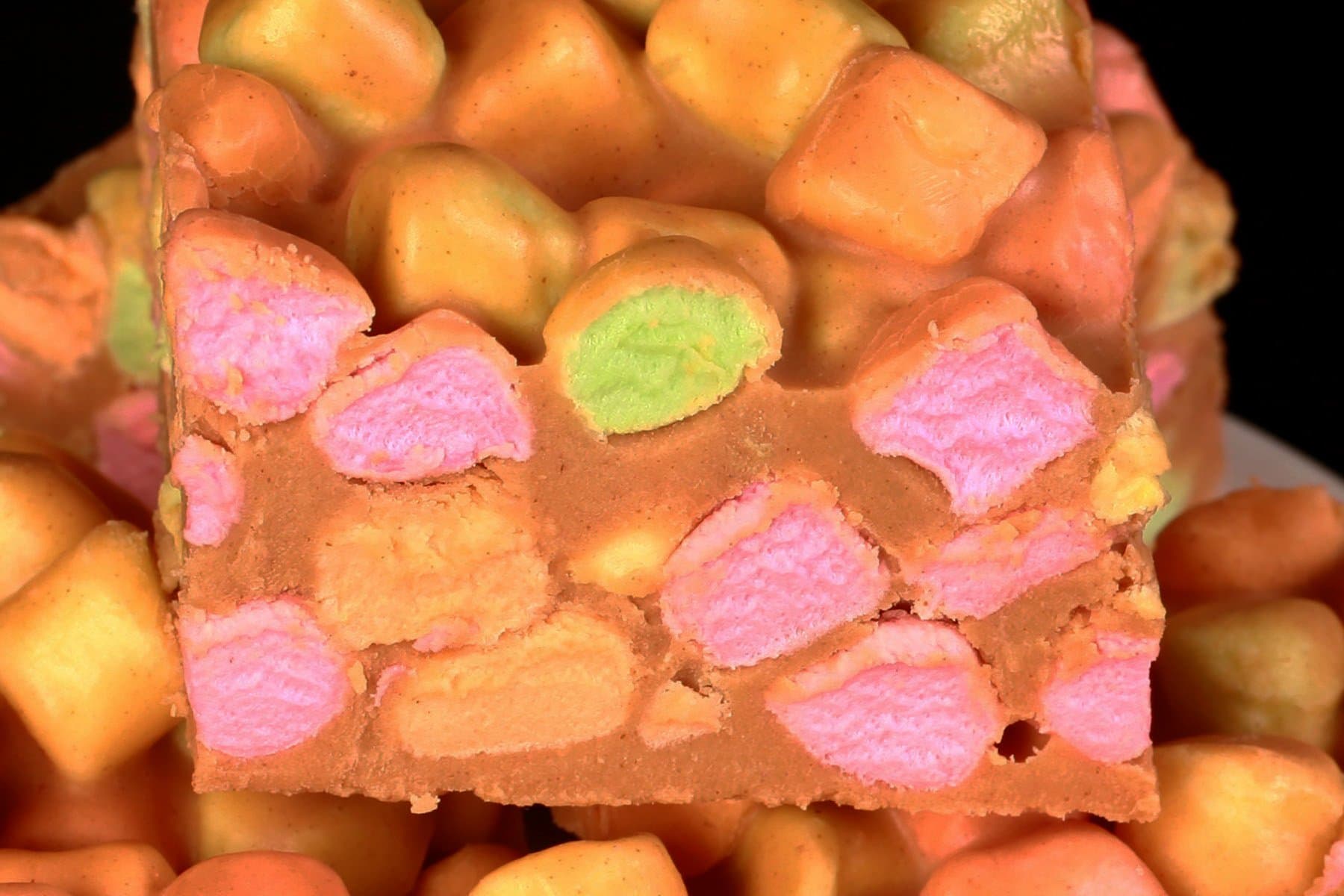 Close up view of marshmallow butterscotch bars - rainbow marshmallows held together with a butterscotch and peanut butter fudge.