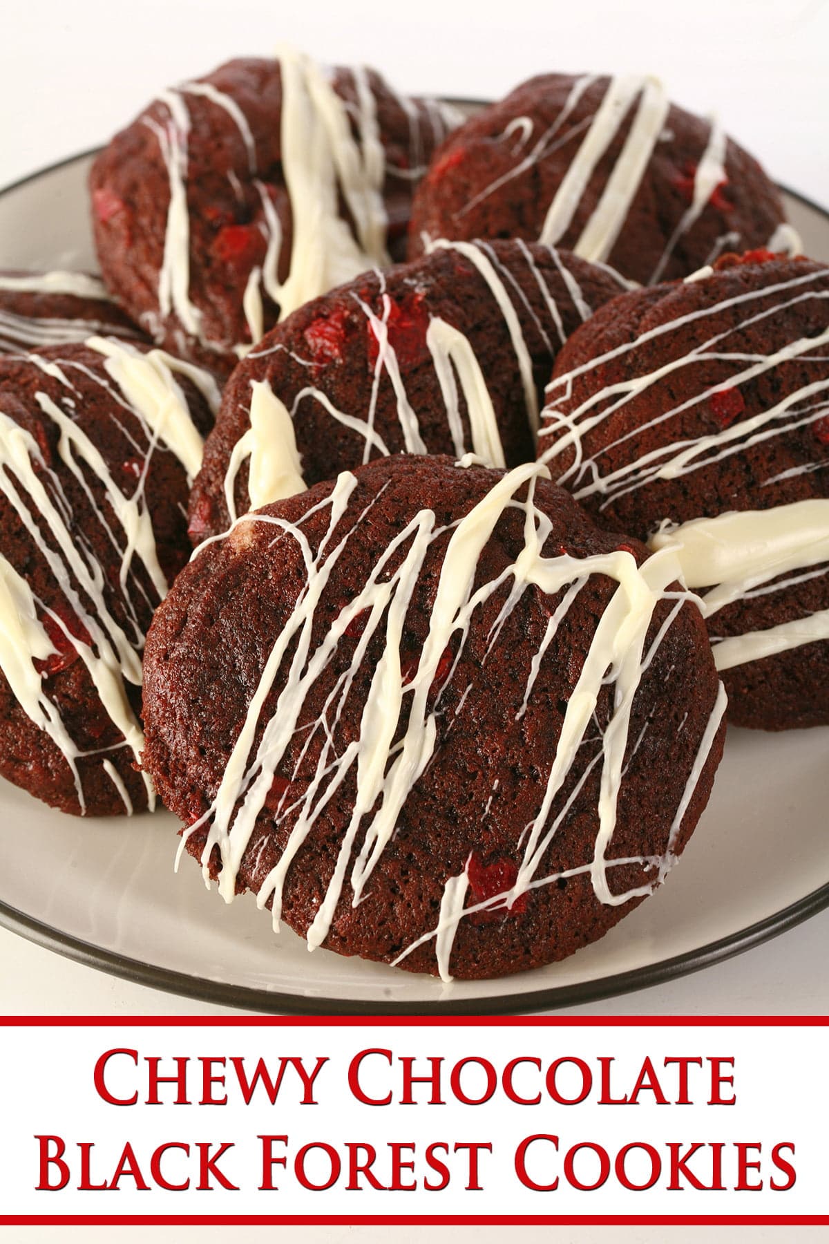 A plate of chewy chocolate black forest cookies, studded with bits of maraschino cherry and drizzled in white chocolate.