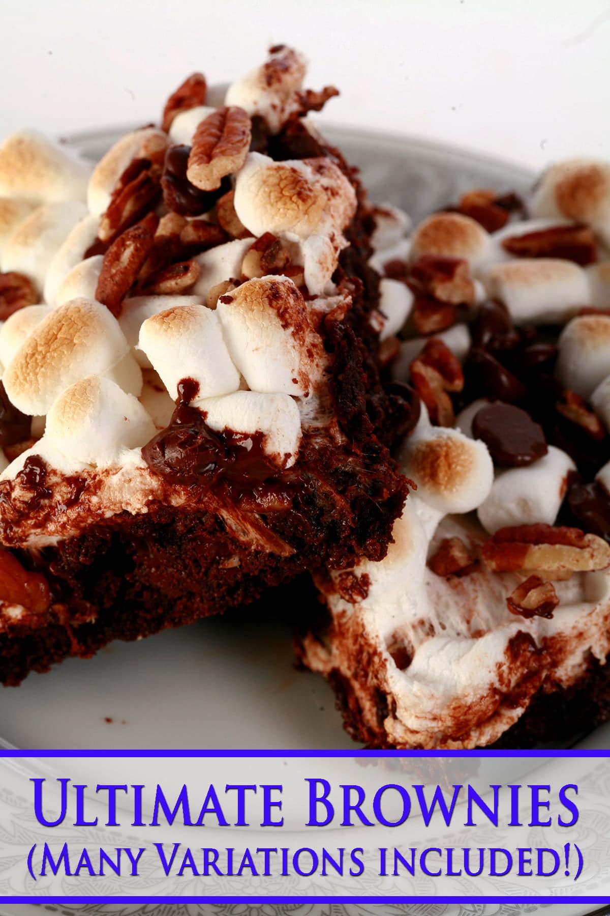 A close up view of two rocky road brownies - double chocolate walnut brownies with toasted mini marshmallows, chocolate chips, and chopped pecans on top.