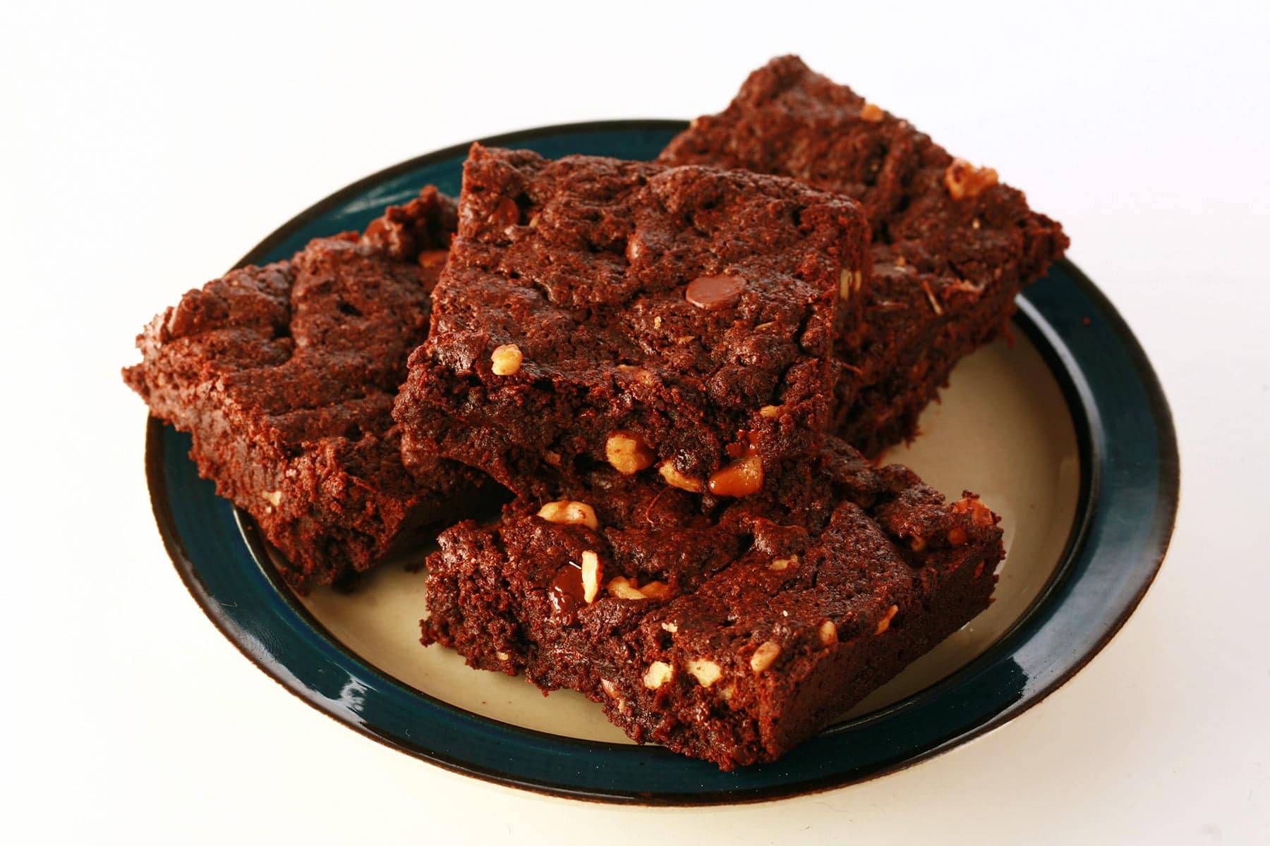 A small plate, piled with 4 double chocolate walnut brownies.