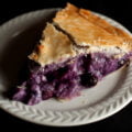 A slice of a creamy blueberry amaretto pie, on a small white plate.