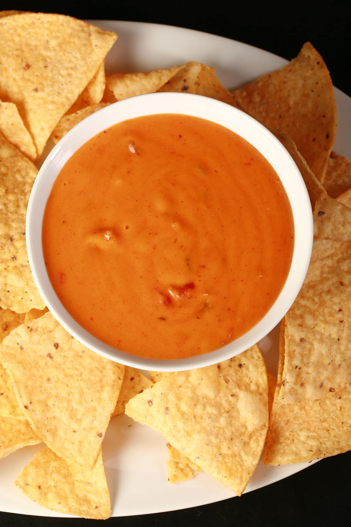 A bowl of real cheese dip, surrounded by tortilla chips.