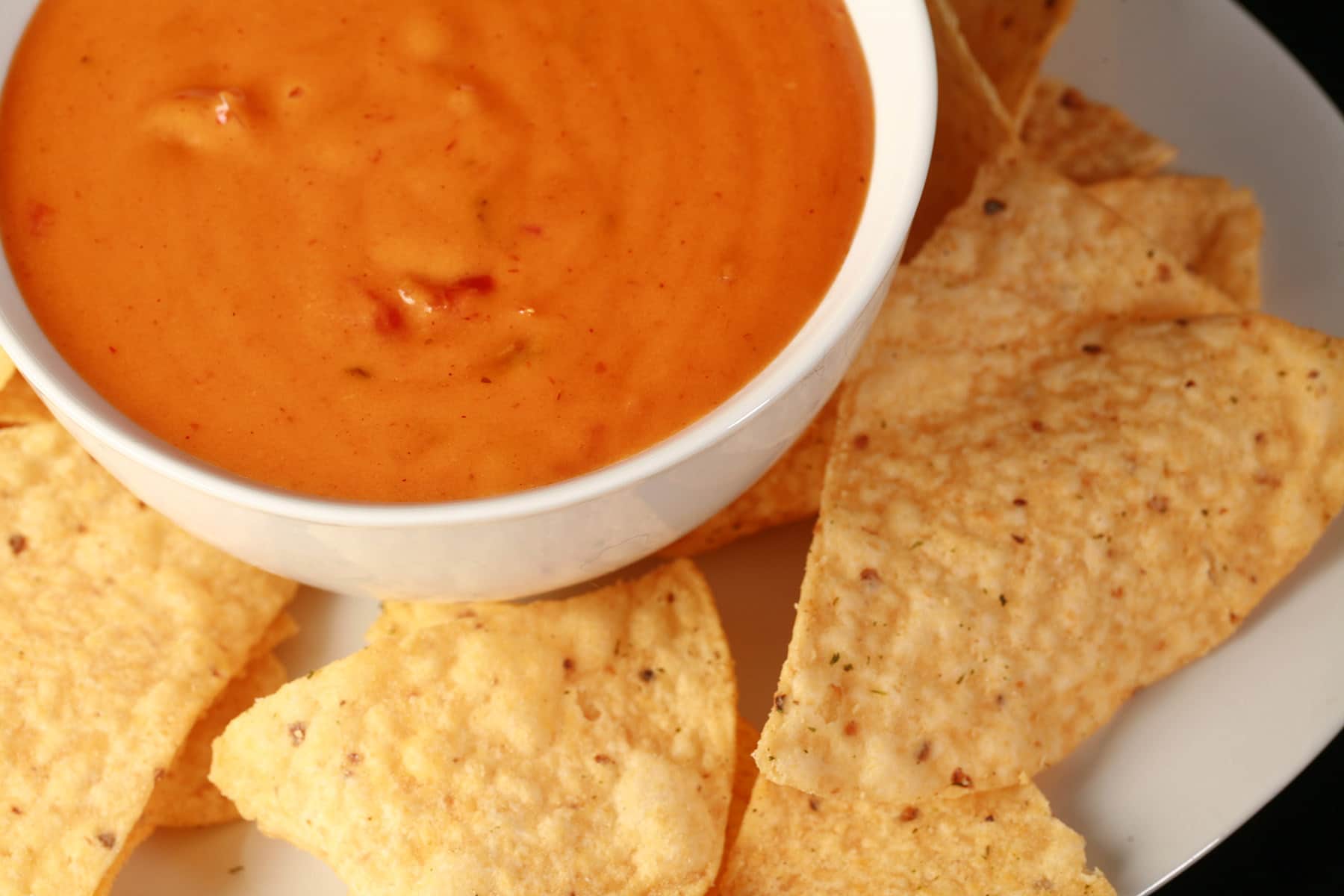 A bowl of real cheese queso dip, surrounded by tortilla chips.