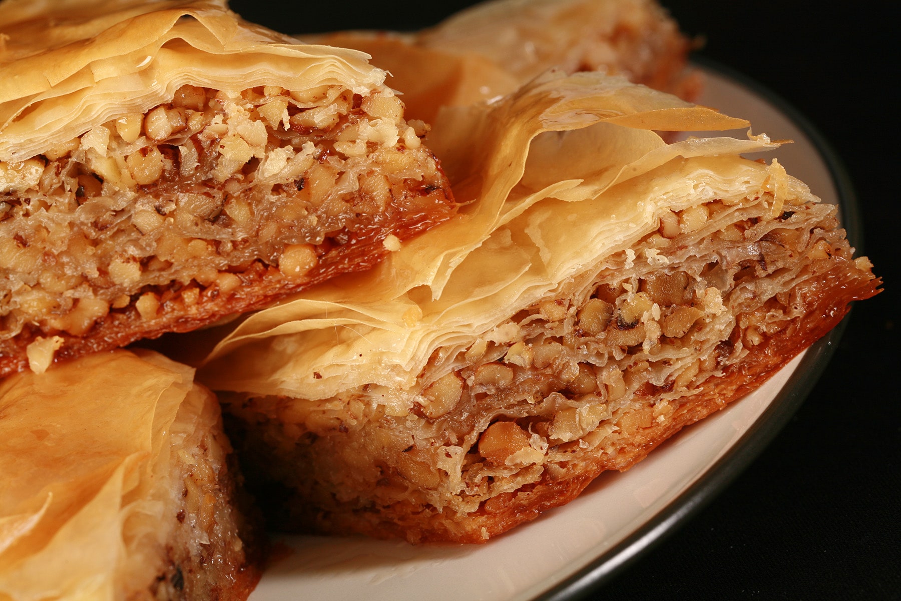 A close up view of a diamond shaped maple walnut baklava on a small white plate.