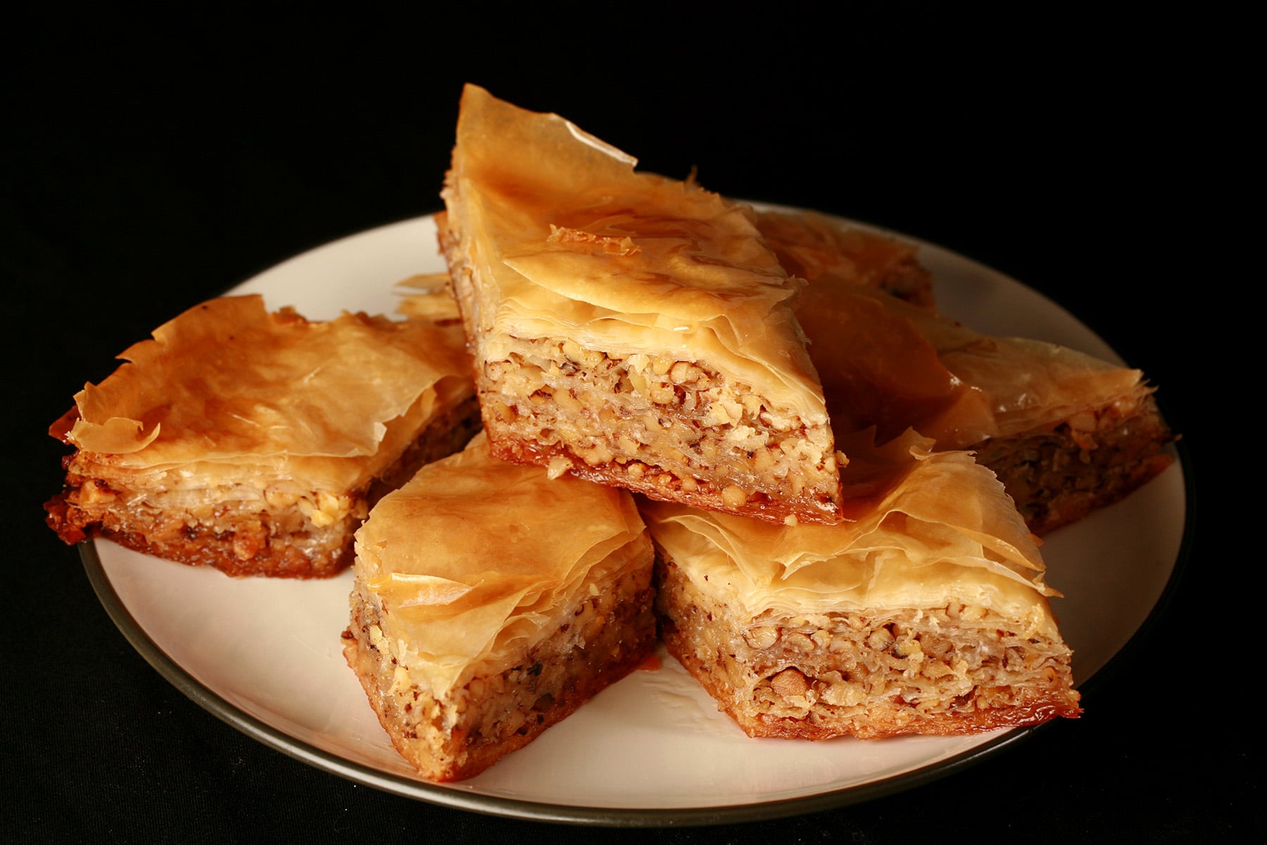 Diamond shaped pieces of maple-walnut baklava, on a small white plate.