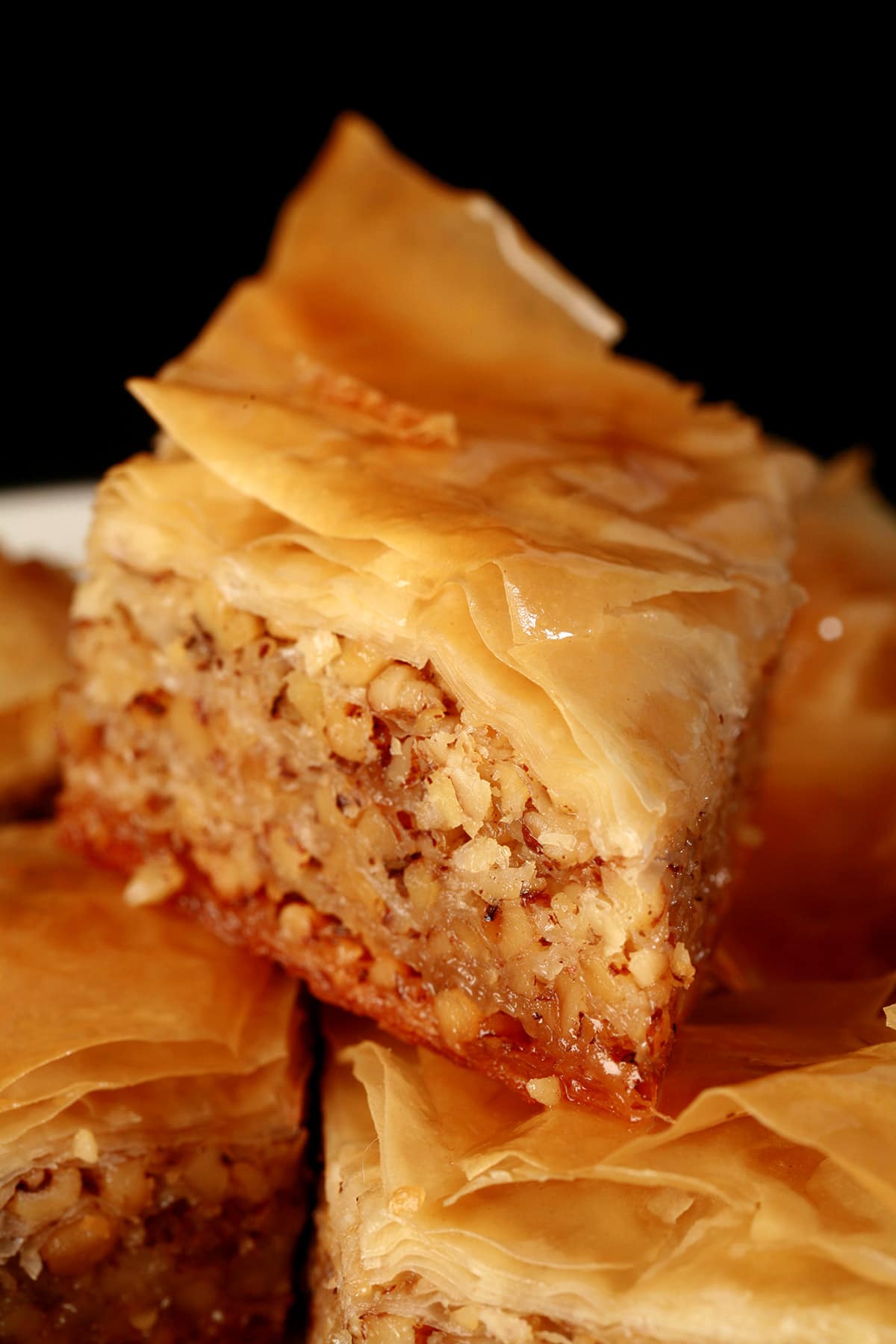 A close up view of a diamond shaped maple walnut baklava on a small white plate.