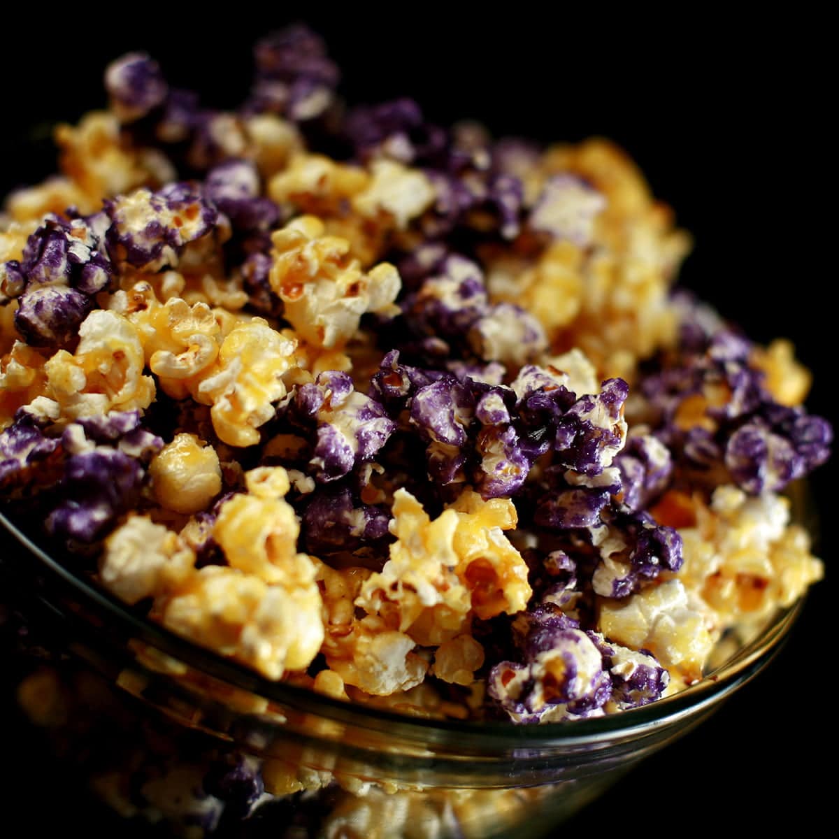 A close up view of a bowl of candy popcorn. The game day popcorn is yellow and purple, themed around a sports team.