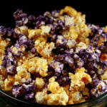 A close up view of a bowl of glazed popcorn. The game day popcorn is yellow and purple, themed around a sports team.