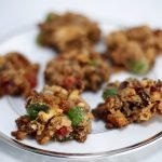 A plate of fruitcake cookies - darkish brown cookies with nuts and chunks of red and green glaceed cherries throughout.