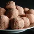 A small plate with a pile of cocoa-coated milk chocolate chai truffles.