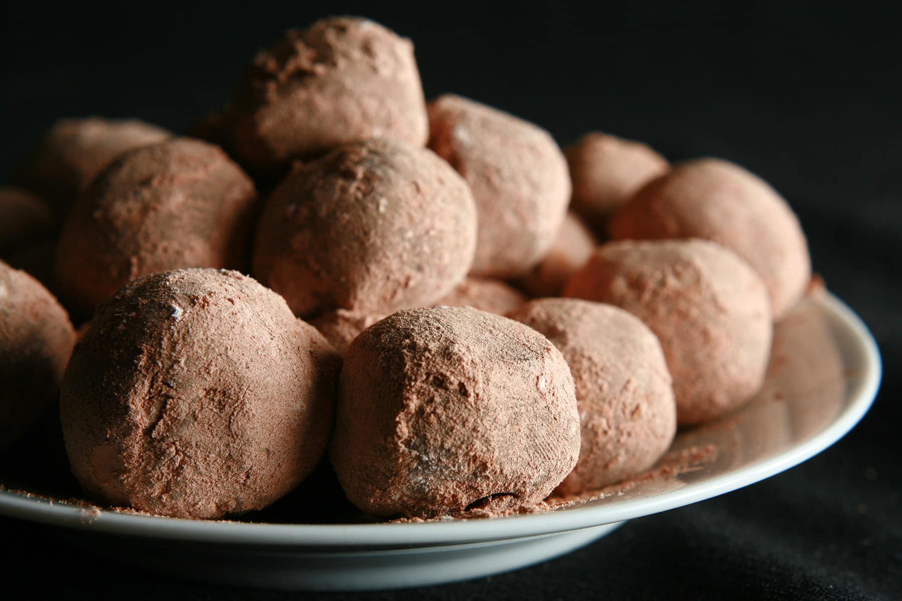 A small plate with a pile of cocoa-coated milk chocolate chai truffles.