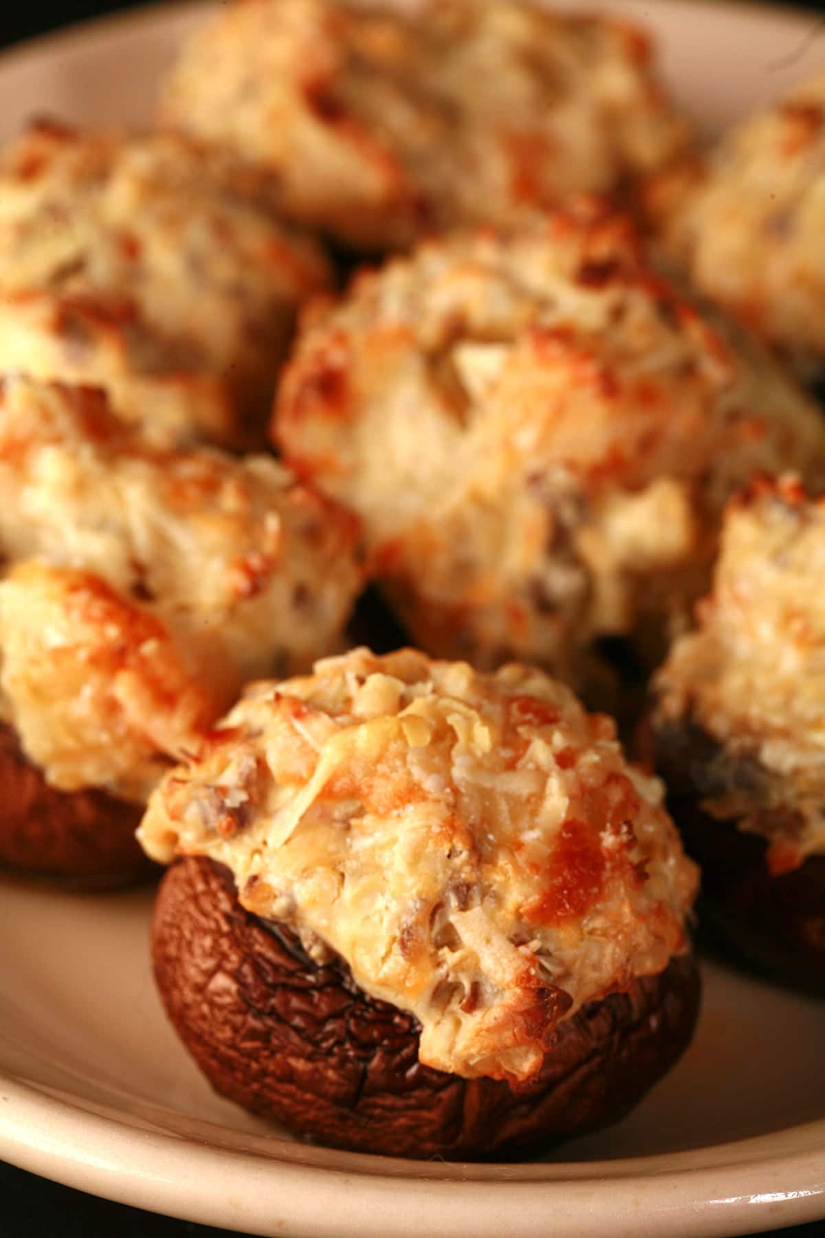 Golden brown shrimp and artichoke stuffed mushrooms on a tan plate.