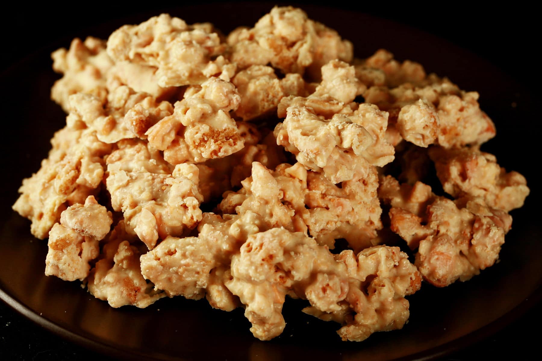 Close up view of homemade Clodhoppers candy: clusters of cashew pieces, graham crackers, and white chocolate.