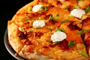 A whole Perogie Pizza - bacon, green onions, cheddar cheese, cheesy potatoes, and sour cream!