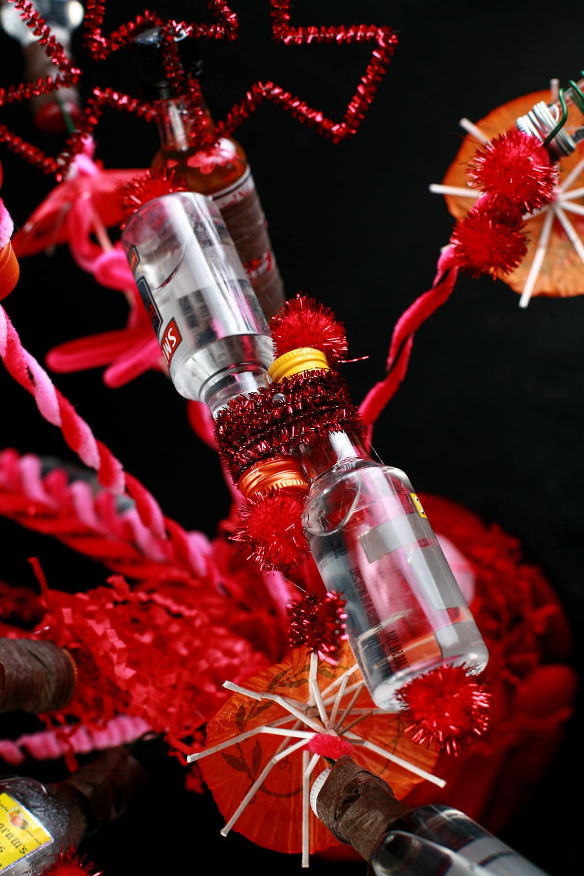 A close up view of a "bouquet" made from mini booze bottles.  Each are wrapped in wire and adored with things like pipe cleaners, mini umbrellas, and pom poms.